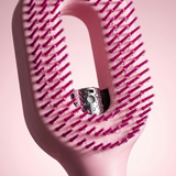 Macro close-up of the chrome mist nozzle and flexible pink bristles with water droplets